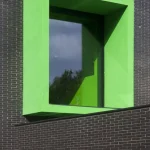 Fenêtre encastrée verte sur mur en briques noires