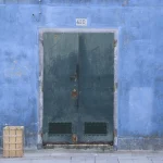 Porte verte sur mur bleu avec caisse en bois