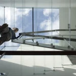 Vue en contre-plongée d’un homme sur un escalier en spirale en verre