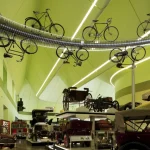 Exposition de vélos et voitures anciennes dans un musée moderne