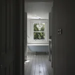 Salle de bain lumineuse avec baignoire et fenêtre ouverte