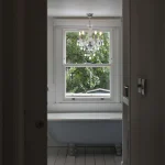 Salle de bain avec baignoire sur pattes et fenêtre donnant sur un jardin