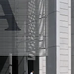 Homme marchant devant un bâtiment moderne en béton