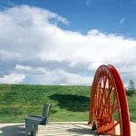 Banc en pierre à côté d'une roue rouge géante en plein air
