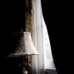 Lampe antique près de la fenêtre dans une pièce sombre