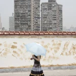 Femme avec parapluie devant immeubles