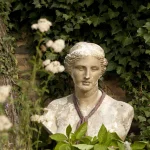 Buste de statue classique entouré de feuillage vert