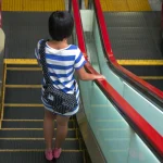 Personne en haut d'un escalator dans un centre commercial