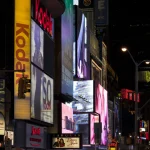 Affiches lumineuses et circulation nocturne dans une rue animée