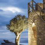 Arbre éclairé près d'une ancienne construction en bord de mer, au crépuscule