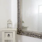Miroir orné avec lanterne sur petite table blanche