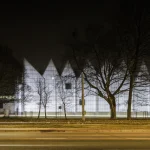 Bâtiment Moderne Illuminé la Nuit derrière des Arbres
