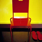 Chaise et tongs rouges sur fond jaune
