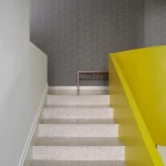 Escalier moderne avec rampe jaune dans un intérieur minimaliste