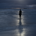 Silhouette solitaire face à la mer sous un ciel dramatique