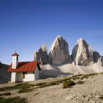 Petite chapelle devant les montagnes rocheuses sous un ciel bleu