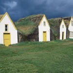 Maisons traditionnelles au toit en herbe sous un ciel orageux