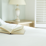 Livre ouvert sur lit avec lampe et table de chevet