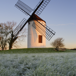 Moulin à vent au lever du soleil sur une prairie givrée
