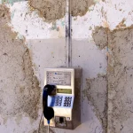 Téléphone public mural sur fond de mur en béton