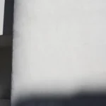 Un homme debout contre un mur blanc