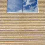 Fenêtre avec réflection du ciel dans un mur strié