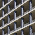 Bâtiment en béton avec arcades et une personne sur le balcon