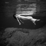 Femme flottant sous l'eau en robe blanche