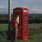 Cabine téléphonique rouge sur fond de campagne verte