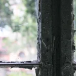 Fenêtre ancienne avec peinture écaillée et vue floue sur l'extérieur