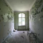 Chambre abandonnée avec peinture écaillée et fenêtres lumineuses