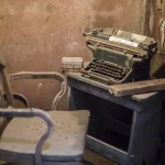 Vieille machine à écrire sur bureau ancien dans pièce délabrée