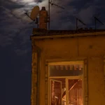 Maison sous la lune avec antennes sur le toit