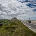 Route côtière avec tramway et maison sous ciel nuageux