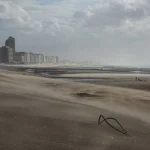 Plage déserte avec bâtiments en arrière-plan sous un ciel nuageux