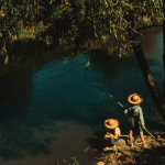 Pêcheur et enfant au bord d'une rivière
