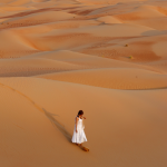 Femme marchant dans le désert au coucher du soleil