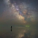Personne observant la Voie lactée réfléchie sur l'eau