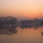 Coucher de soleil sur lac avec arbres en reflet
