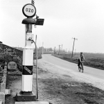 Station-service vintage avec un cycliste sur une route rurale