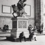 Place publique avec sculpture classique et passants