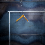 Cintre en bois suspendu sur une tringle métallique devant un mur industriel