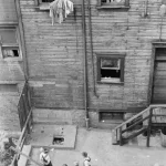 Enfants jouant dans une cour arrière devant un immeuble délabré