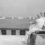 Couple sur le bord de mer regardant les voiliers en noir et blanc