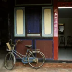 Vélo ancien devant bâtiment coloré asiatique.