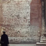 Femme âgée marchant devant un mur décrépit