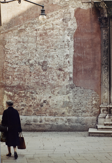 AKG6149885.webp Femme âgée marchant devant un mur décrépit – Image 1