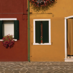 Façades colorées avec volets et rideaux dans une rue pavée.