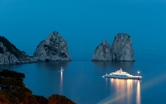 AKG6206436.webp Yacht lumineux au large des formations rocheuses – Image 1