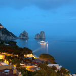 Paysage nocturne côtier avec vue sur des formations rocheuses et bateau illuminé